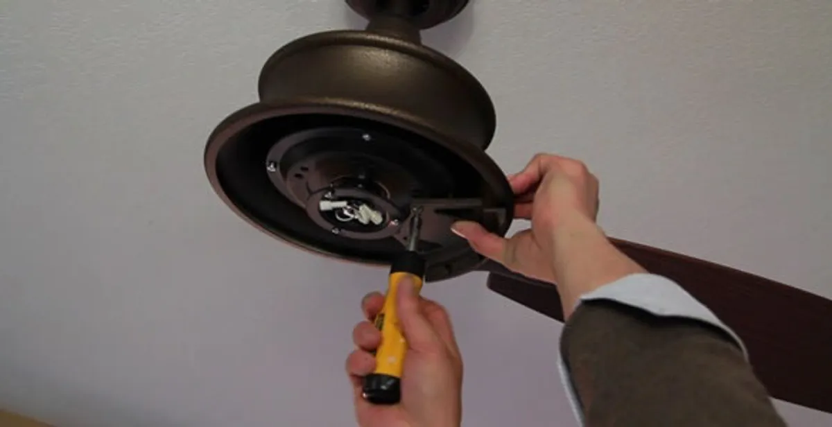 Electrician installing ceiling fan mounting bracket and fixture in Miami, FL