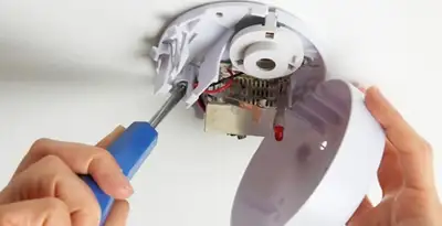 Certified technician wiring smoke detector during installation in Miami, FL